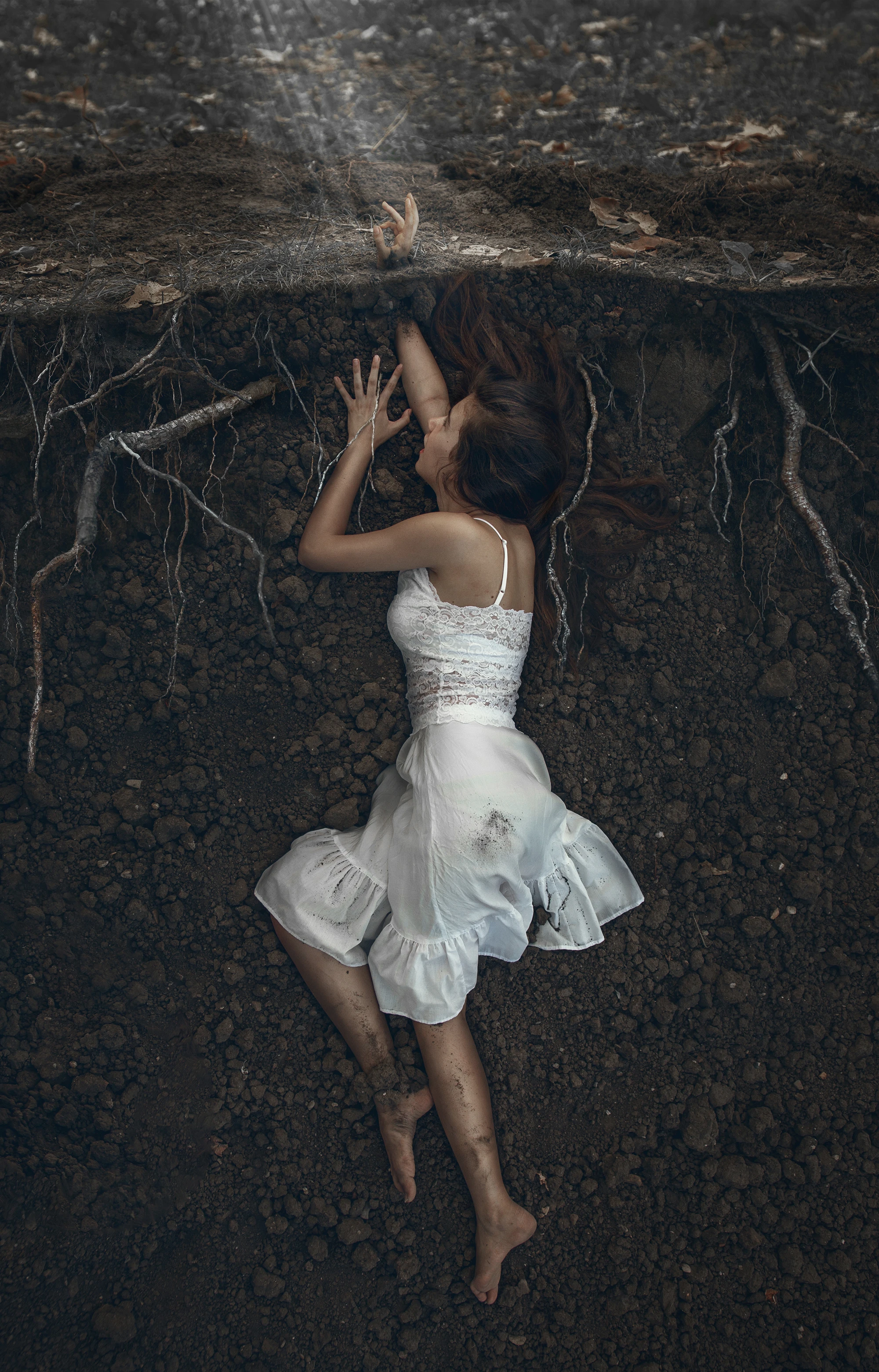 high-end compositing seamless integration of elements showing woman lying beneath the earth, surrounded by soil and tree roots, reaching upward.
