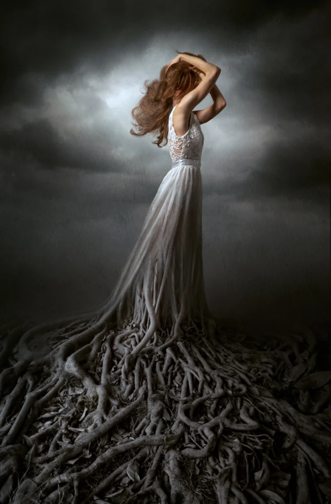 retouching portfolio example of compositing on woman in a white lace dress transforming into tree roots against a stormy sky.