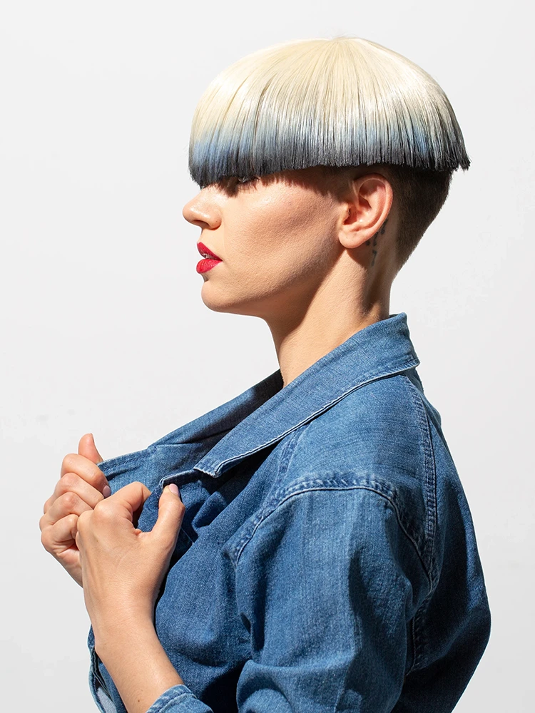Profile portrait with a geometric bowl-cut hairstyle transitioning from platinum blonde to deep blue.